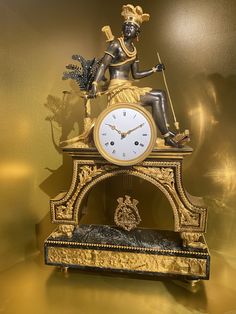 a clock that is sitting on top of a stand with a statue in front of it