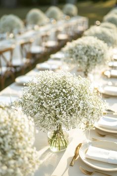 the table is set with white flowers and place settings