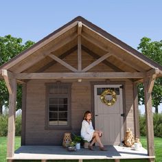 a woman sitting on top of a porch next to a potted plant in front of a house