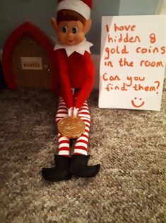 an elf is sitting on the floor next to a sign