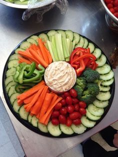 a platter filled with cucumbers, tomatoes, broccoli and carrots