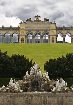 an image of a fountain in front of a large building with columns and arches on it