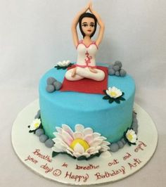 a birthday cake with a woman doing yoga on the top, and flowers around it