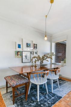 a dining room table with chairs and pictures on the wall