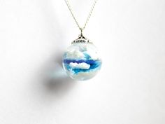 Capture the essence of a bright day with our unusual Aqua Blue Sky Marble Necklace. This piece, perfect as a gift, encapsulates fluffy white clouds within a 20mm aqua-blue resin sphere. The vibrant hue catches the sun beautifully, offering a wearable piece of the sky. Each necklace is handcrafted with high-quality materials and meticulous attention to detail, ensuring a unique and standout piece. The resin sphere hangs on a sterling silver chain. Due to popular requests blue sky earrings are now Marble Necklace, Celestial Necklace, Blue Clouds, White Clouds, Resin Necklace, Aqua Blue, Sterling Silver Chains, Silver Chain, Jewelry Necklace Pendant