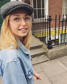 a woman wearing glasses and a hat on the sidewalk