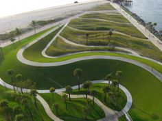 an aerial view of a grassy area next to the ocean with trees on both sides