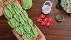 crocheted flowers are being held up by someone's hands on a table