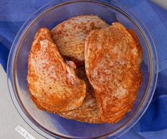 two pieces of bread sit in a glass bowl on a blue cloth covered tablecloth