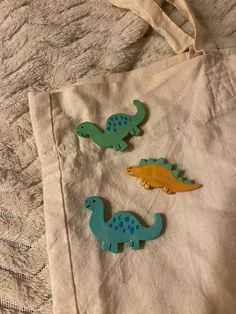 three wooden dinosaurs sitting on top of a white tote bag next to each other