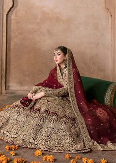 a woman sitting on top of a green couch wearing a red and gold wedding dress