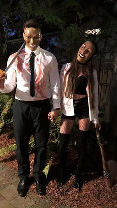 a man and woman dressed up as zombies holding hands while standing next to each other