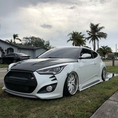 a white and black car parked on the side of a road next to some palm trees