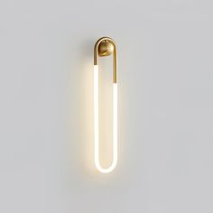 a light that is on the wall in front of a white background with a gold handle