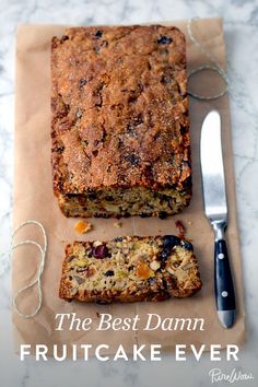 a loaf of fruitcake next to a knife on top of a piece of paper