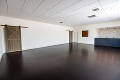 an empty room with white walls and wood floors, two doors are open on the far wall