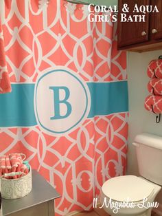 a bathroom decorated in coral and white with monogrammed shower curtain