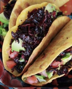 two tacos with lettuce, tomatoes and other toppings on a plate