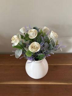 a white vase filled with flowers on top of a wooden table