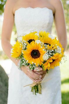 a bride holding a bouquet of sunflowers