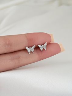 These stunning sterling silver butterfly earring studs will make you stand out from the crowd in all the right ways! They feature a beautiful minimalist design, making them the perfect accessory to add a touch of sophistication to any ensemble. Treat yourself or someone else to these exquisite sterling silver butterfly earring studs to add a stylish flourish to any look. Material: solid sterling silver, cubic zirconia,  Finish: Platinum, or gold plated over sterling silver. Size: 9mm Sold as a p Aesthetic Earrings Studs, Silver Earrings With Butterfly Charm, Silver Dainty Butterfly Earrings, Dainty Silver Butterfly Earrings, Silver Cubic Zirconia Butterfly Earrings, White Butterfly Cubic Zirconia Earrings, Butterfly Shaped White Cubic Zirconia Earrings, White Butterfly-shaped Cubic Zirconia Earrings, Silver Butterfly Charm Earrings With Cubic Zirconia