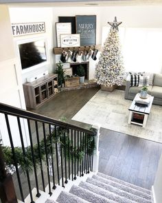 a living room filled with furniture and a christmas tree on top of a wooden floor