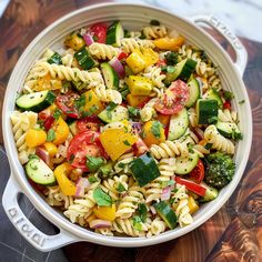 a white bowl filled with pasta salad on top of a wooden cutting board