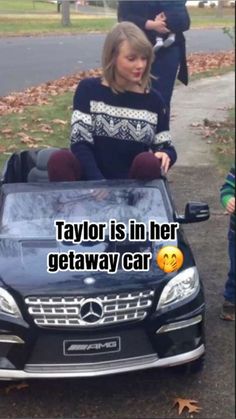 a woman sitting on top of a black car next to a little boy with an emoticive face