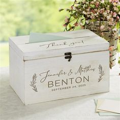 a white wooden box sitting on top of a table next to a vase filled with flowers