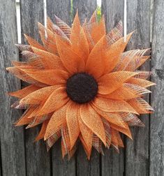 an orange mesh sunflower hanging on a wooden fence