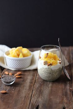 two bowls filled with food sitting on top of a wooden table next to spoons