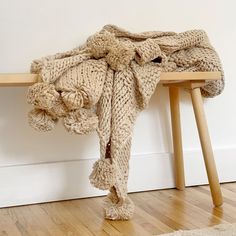 a pile of blankets sitting on top of a wooden table next to a white wall