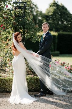 a bride and groom standing in front of a gazebo with their veil blowing in the wind