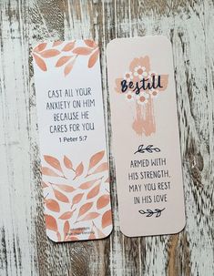 two bookmarks with bible verses on them sitting next to each other against a wooden background