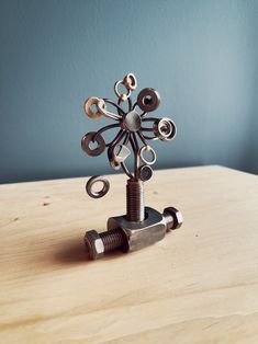 a metal sculpture sitting on top of a wooden table next to a screwdriver