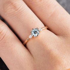 a woman's hand with an engagement ring on top of her finger, showing the center stone