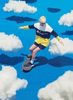 a man riding a skateboard through the air above some clouds on a blue ground