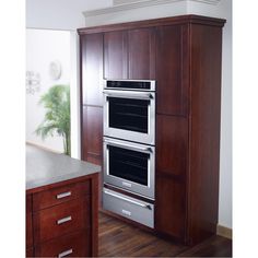 two ovens in a kitchen with wooden cabinets and wood flooring on the walls