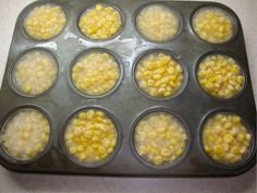 muffin tins filled with corn sitting on top of a counter