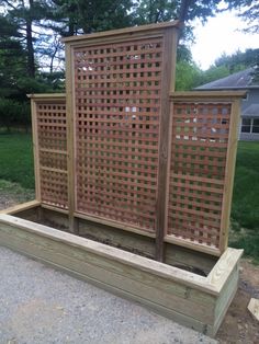 a wooden planter box with lattice design on the top and bottom, in front of some grass