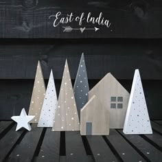 wooden christmas trees are lined up in front of a sign that says east of india