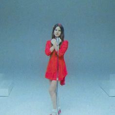 a woman standing in front of a microphone with her hands on her hips and wearing red