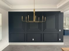 an empty room with black cabinets and a gold chandelier