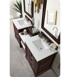 two sinks and mirrors in a bathroom with brown trim on the walls, white countertops and tile flooring