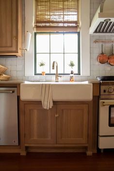 a kitchen with wooden cabinets, white appliances and a window above the dishwasher