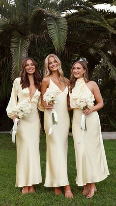 three bridesmaids in yellow dresses posing for the camera with flowers on their bouquets