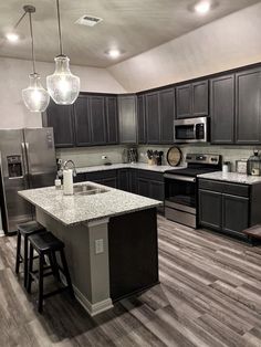 a kitchen with gray cabinets and white counter tops, an island in the middle is surrounded by stools