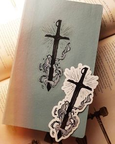 an open book with some stickers on it and a cross in the middle, surrounded by keys