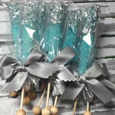 some lollipops are wrapped in plastic and tied with silver ribbon on wooden sticks