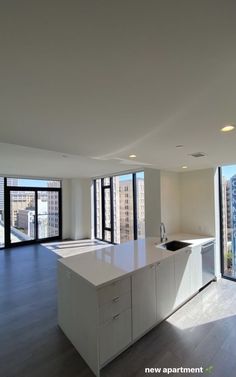 an empty kitchen and living room with large windows in the back drop off wall to the right